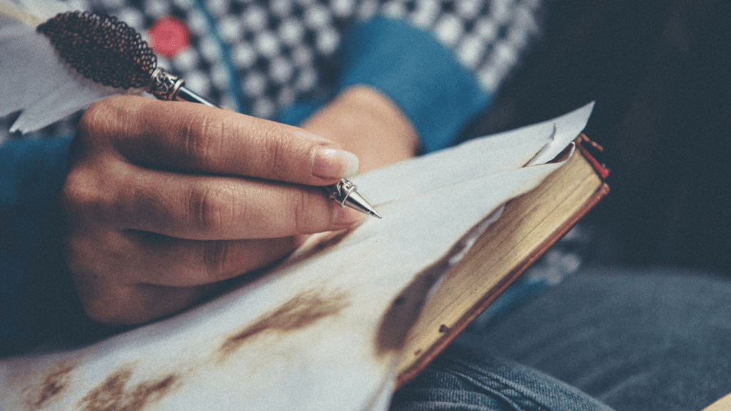 a person holding a pen and writing on a piece of paper