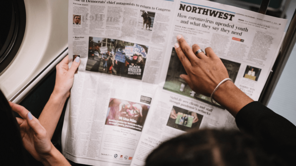 two people looking at a newspaper