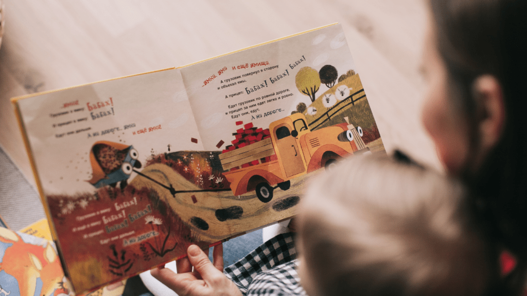 a person is reading a book to a child while sitting on the floor