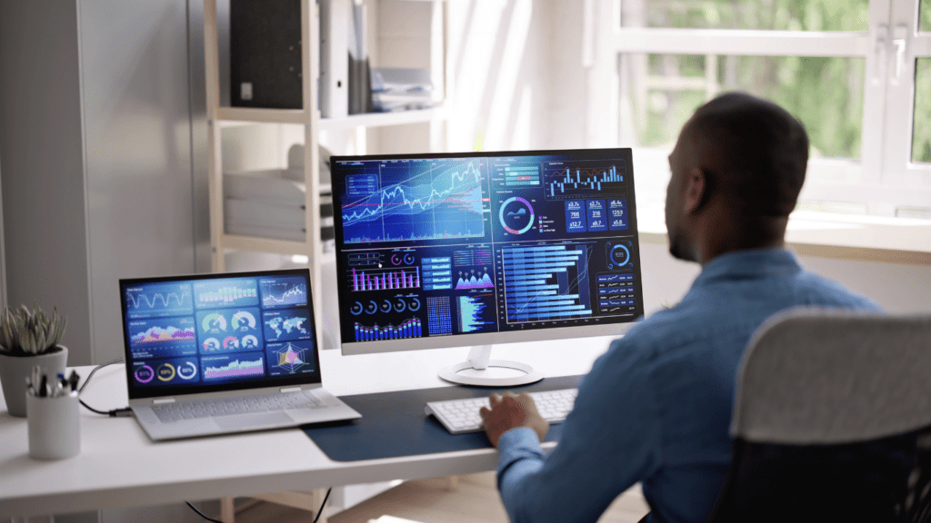 a person sitting at a desk in front of two computer screens