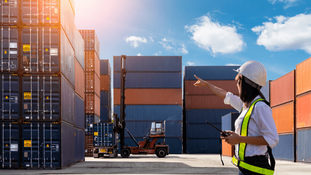 a person in a hard hat pointing at a stack of shipping containers