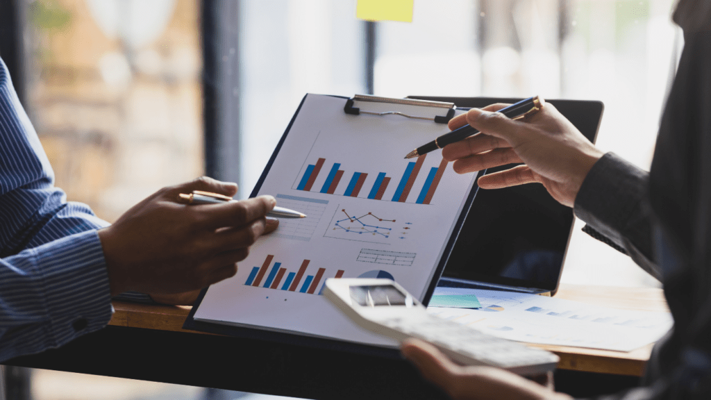 Two business people are looking at graphs on a clipboard