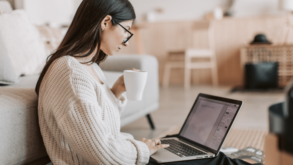 a person sitting on the floor with a laptop and a cup of coffee