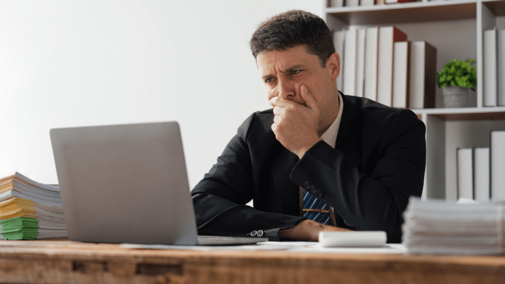 a person in a suit sitting at a desk with a laptop