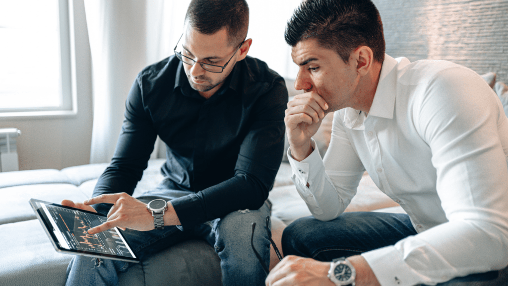 Two business people are looking at graphs on a clipboard