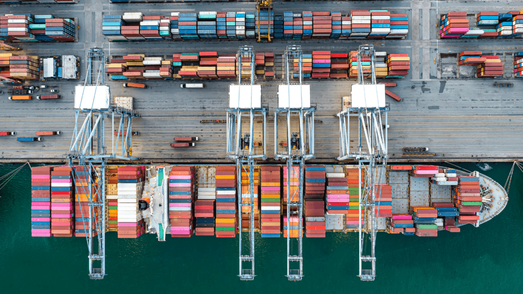 a person in a hard hat pointing at a stack of shipping containers