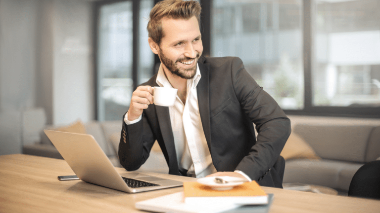 a person in a suit sitting at a desk with a laptop