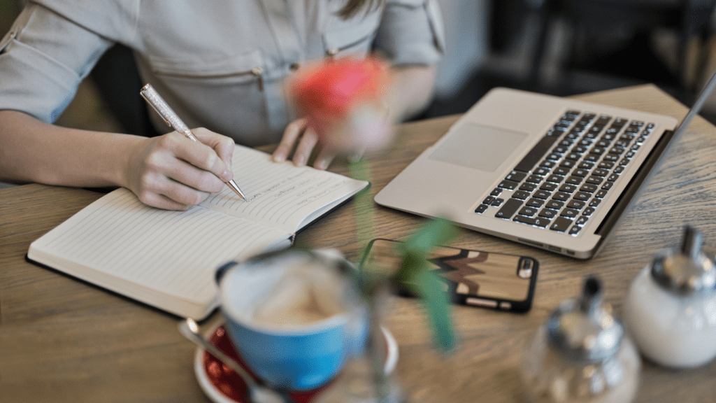 a person is sitting at a table with a notebook and pencil