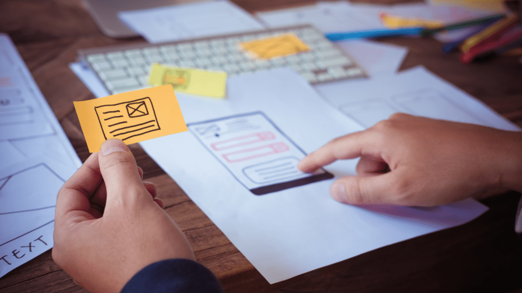 a person is working on their laptop while holding a piece of paper