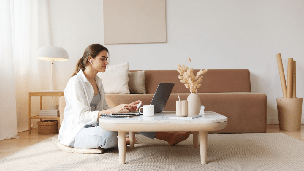 a person sitting on the floor with a laptop and a cup of coffee